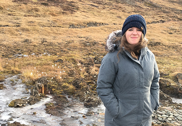 Emily standing in a field wearing a large gray coat