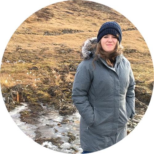 Emily standing in a field wearing a large gray coat